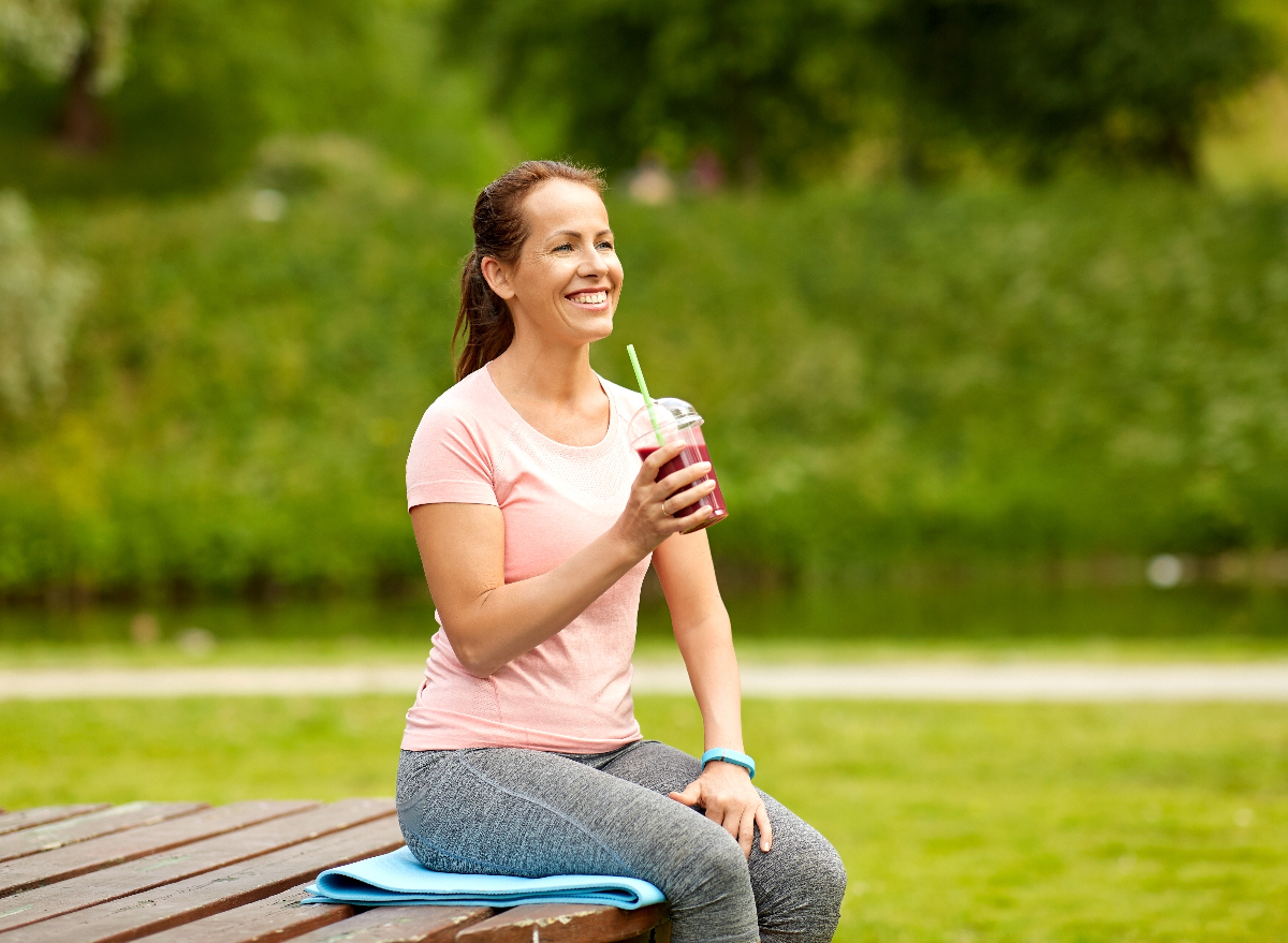 active middle-aged woman enjoying a healthy smoothie outdoors