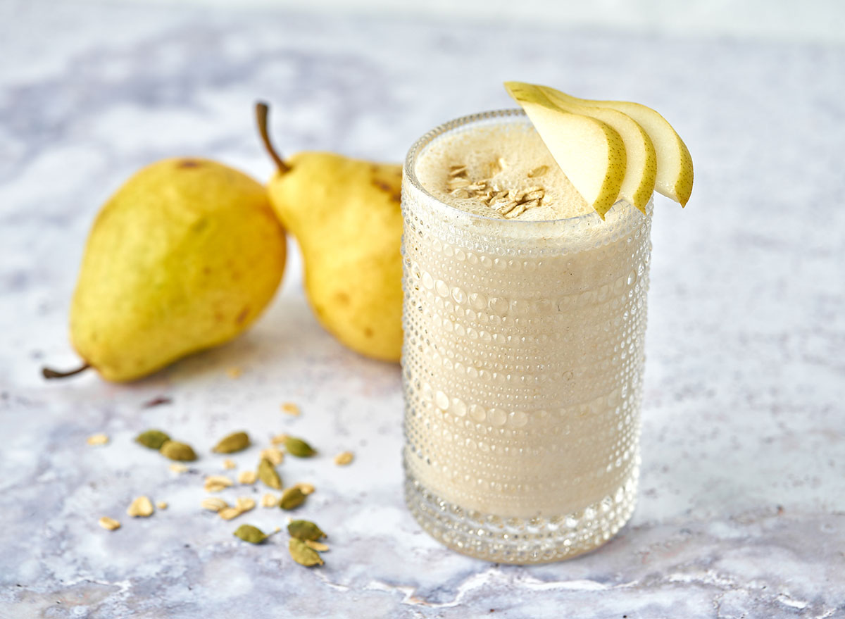 Pear and cardamom smoothie in glass garnished with pear