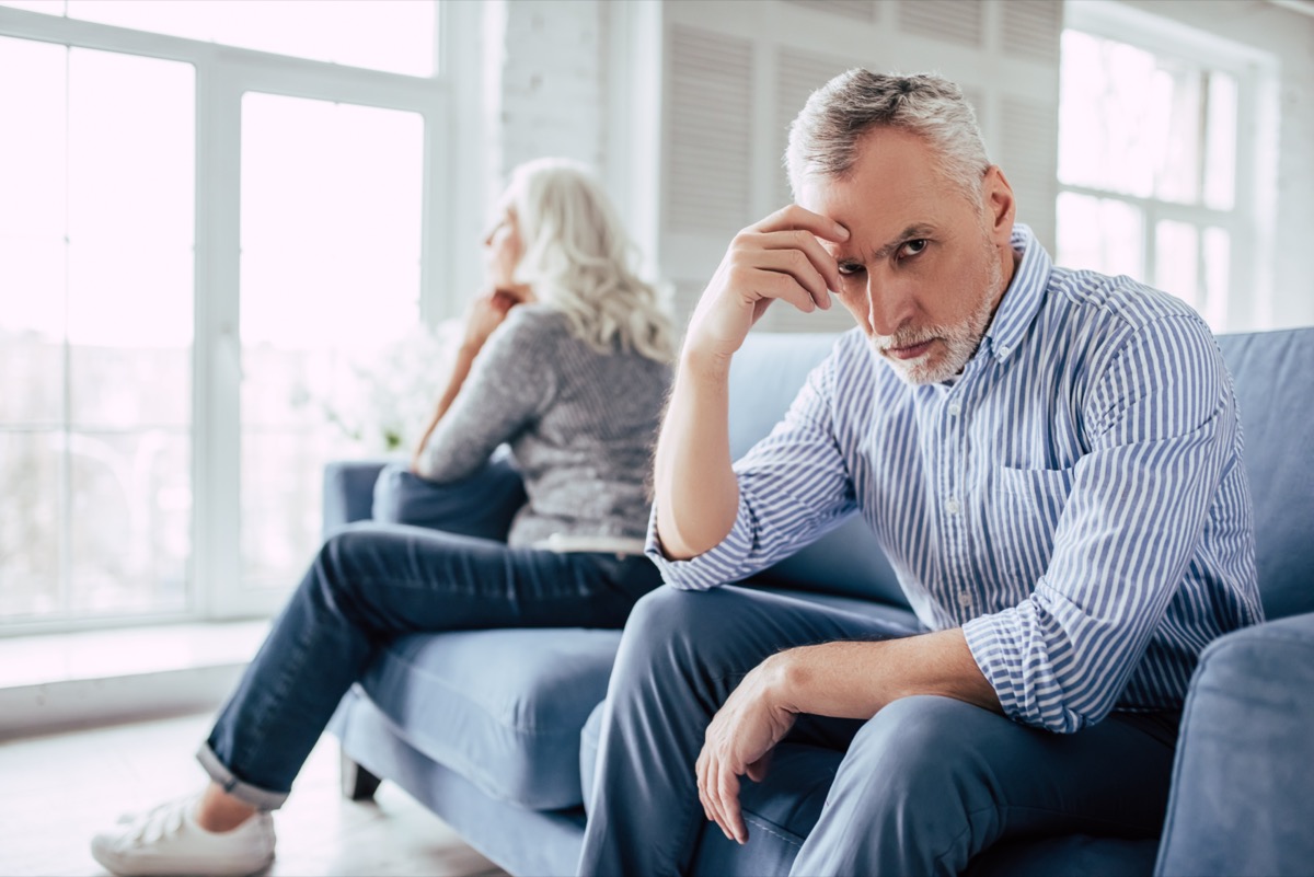 Mature couple sitting on sofa together and looking to opposite sides.