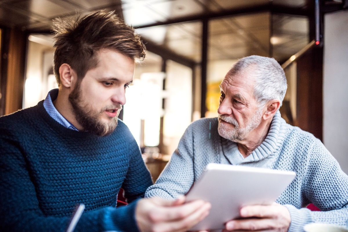 Senior father and young son with tablet in a cafe