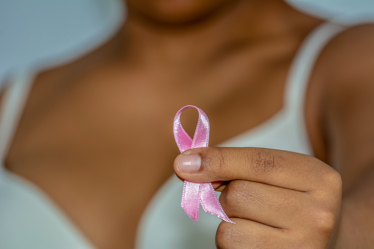 Hand of African woman with pink ribbon against breast cancer