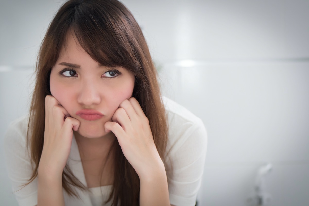 upset woman in the bathroom because of diarrhea, constipation, hemorrhoids, piles