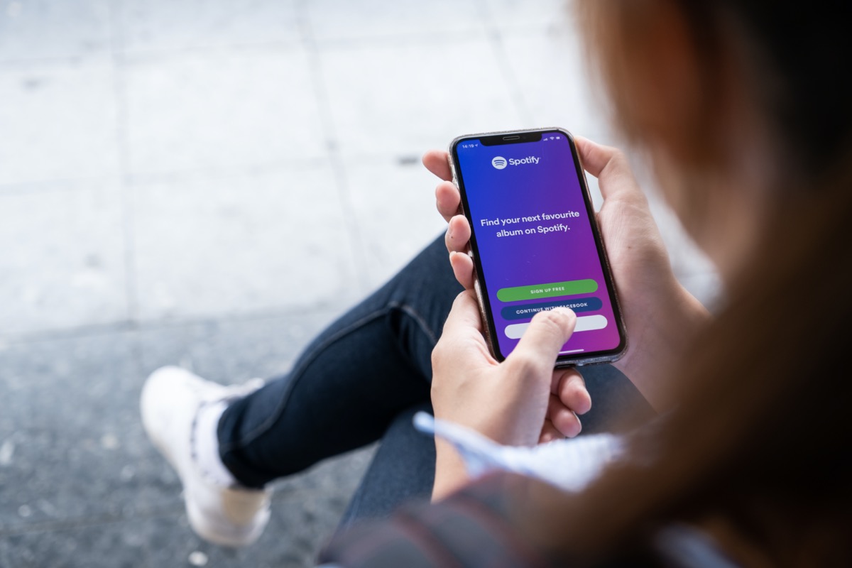 Person holding a new Apple iPhone XS with the Spotify logo on the screen.