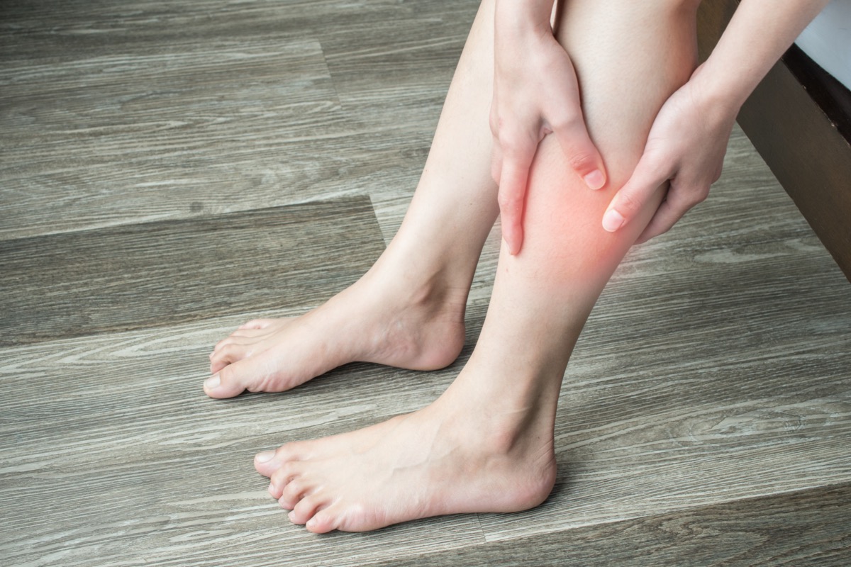 woman's hands holding and massaging her calf, suffering from calf pain