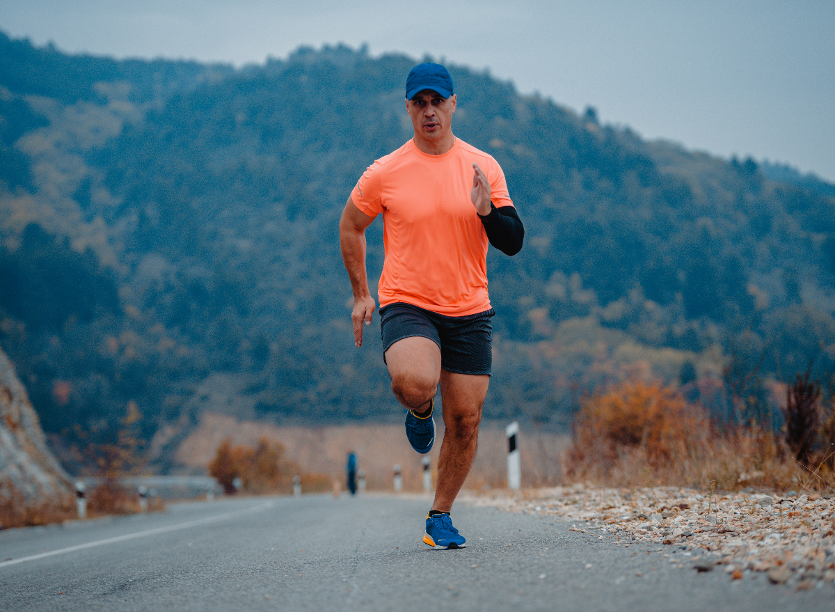 middle-aged man doing intense cardio exercise outdoors on the road