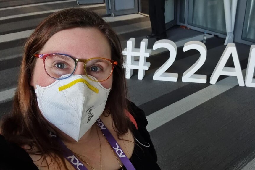 An image of Ash wearing a mask with the letters #22ADC on the ground behind her