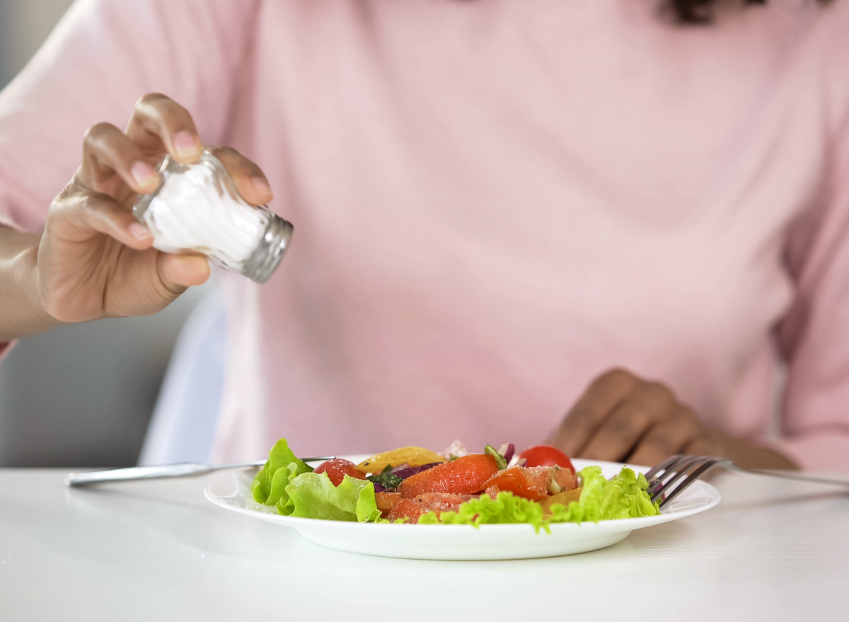 woman adding salt to her food