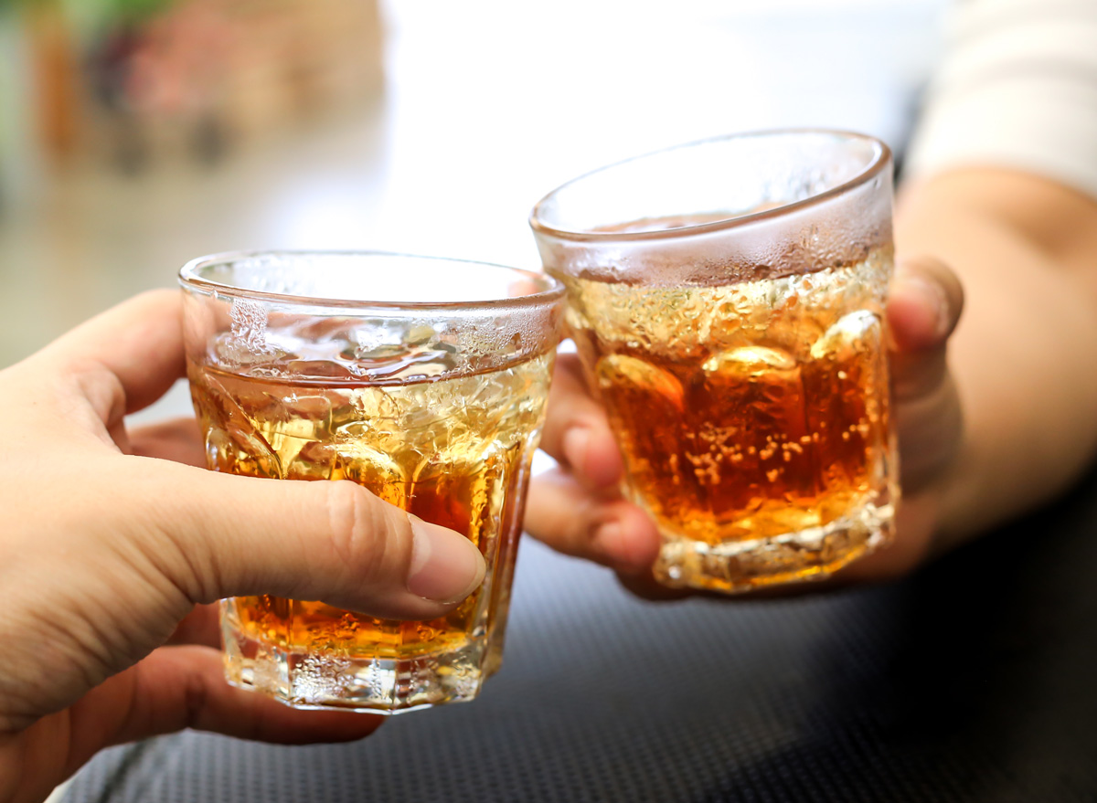 Men cheer with glasses of a whiskey soda alcohol cocktail