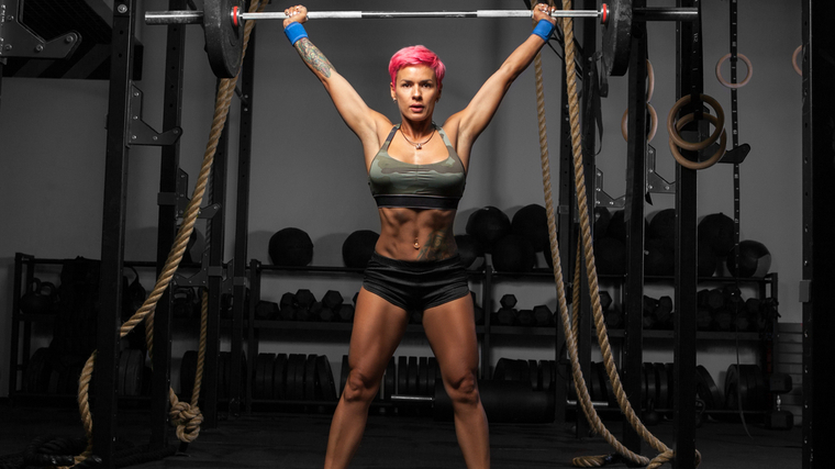 A person locks out a snatch in the gym.