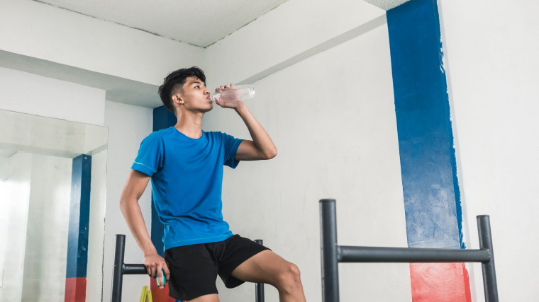 A person rests in between sled pushes and drinks water.