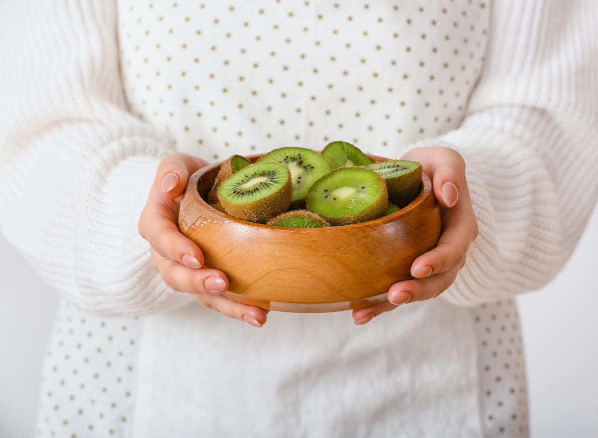 woman holding a plate of kiwis