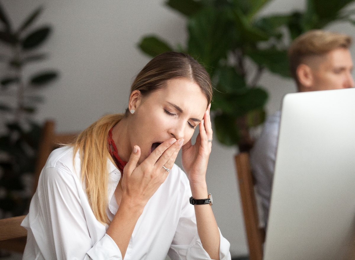 woman wondering why i'm always tired, yawning at work