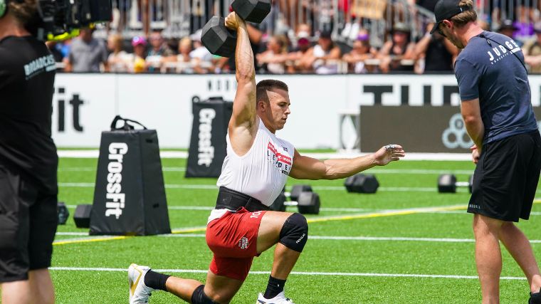 Crossfitter Samuel Cournoyer lunges with a dumbbell overhead.