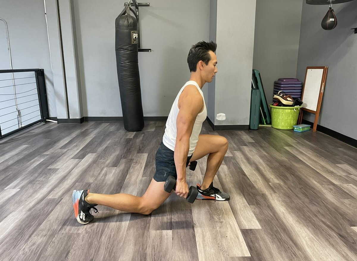 Trainer demonstrating dumbbell reverse lunges for losing belly fat and slowing down aging