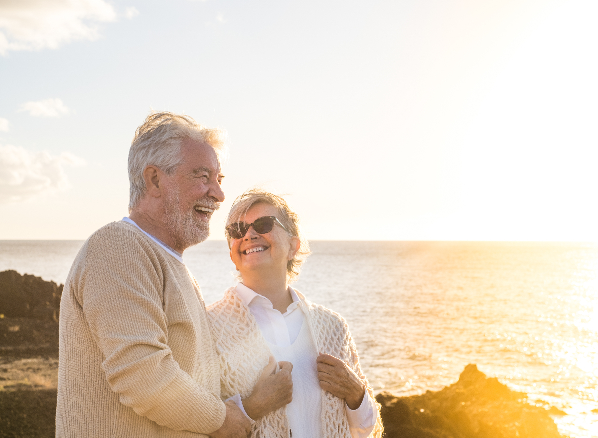 happy elderly couple positive vibes on the beach