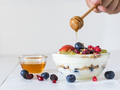 Yogurt bowl topped with mixed berries and honey.